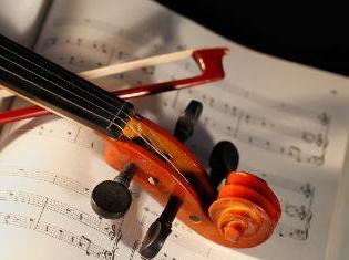 A violin and bow laying on a sheet of music.